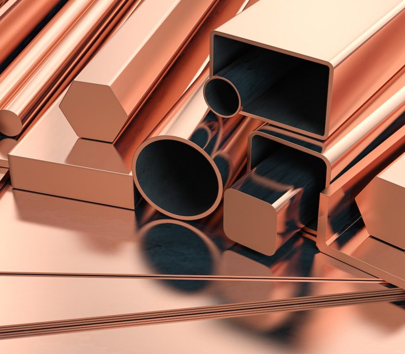 Copper tubes and different profiles in warehouse background. Different copper metal rolled products.